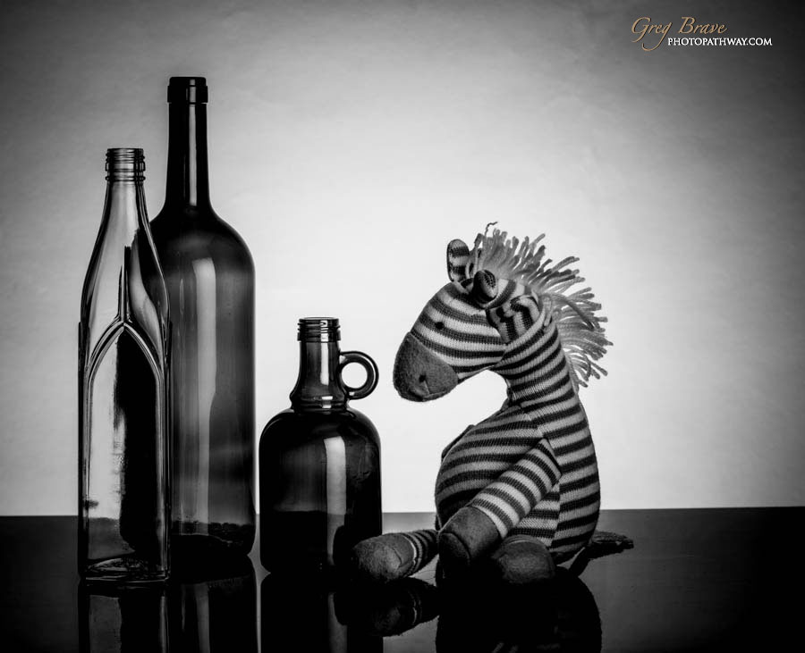 Still life with bottles and toy horse in black and white by greg brave