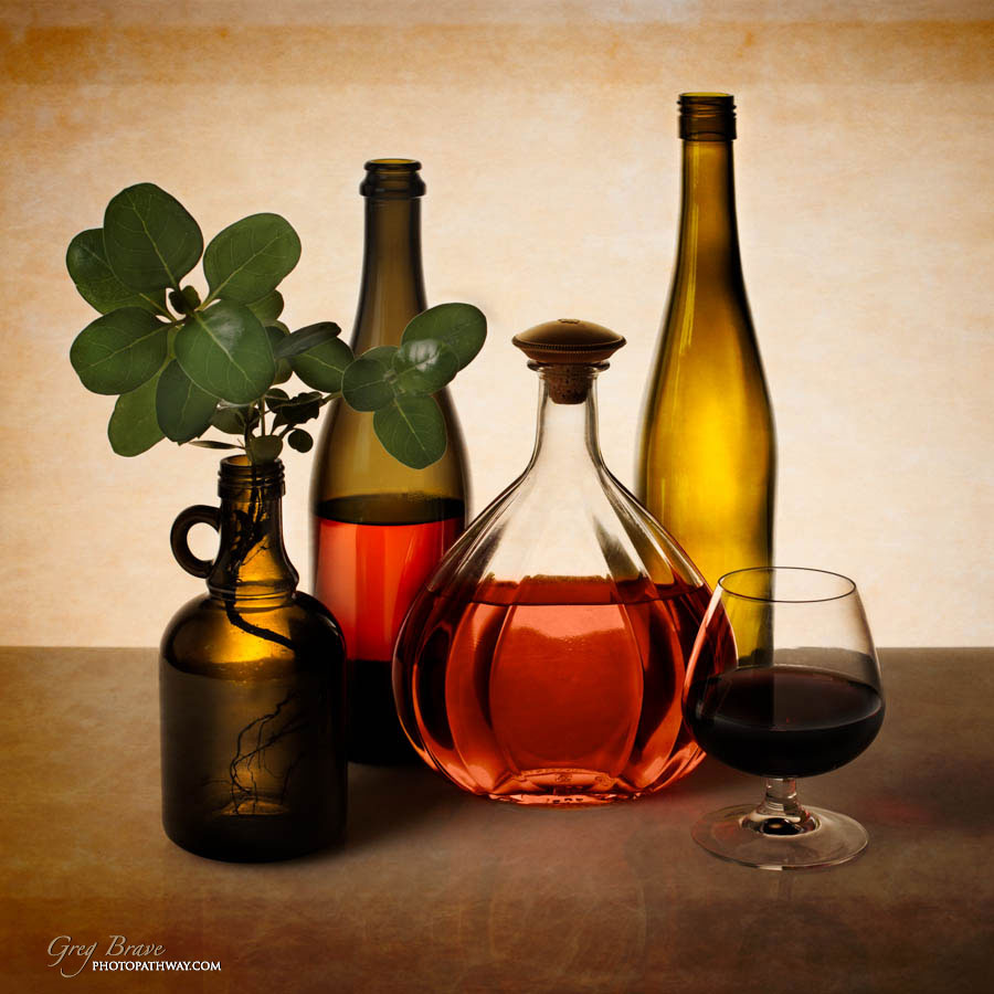 Still life with bottles glass and flora in color by greg brave