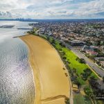 Aerial view of Brighton Beach coastline with Melbourne CBD skyscrapers in the distance